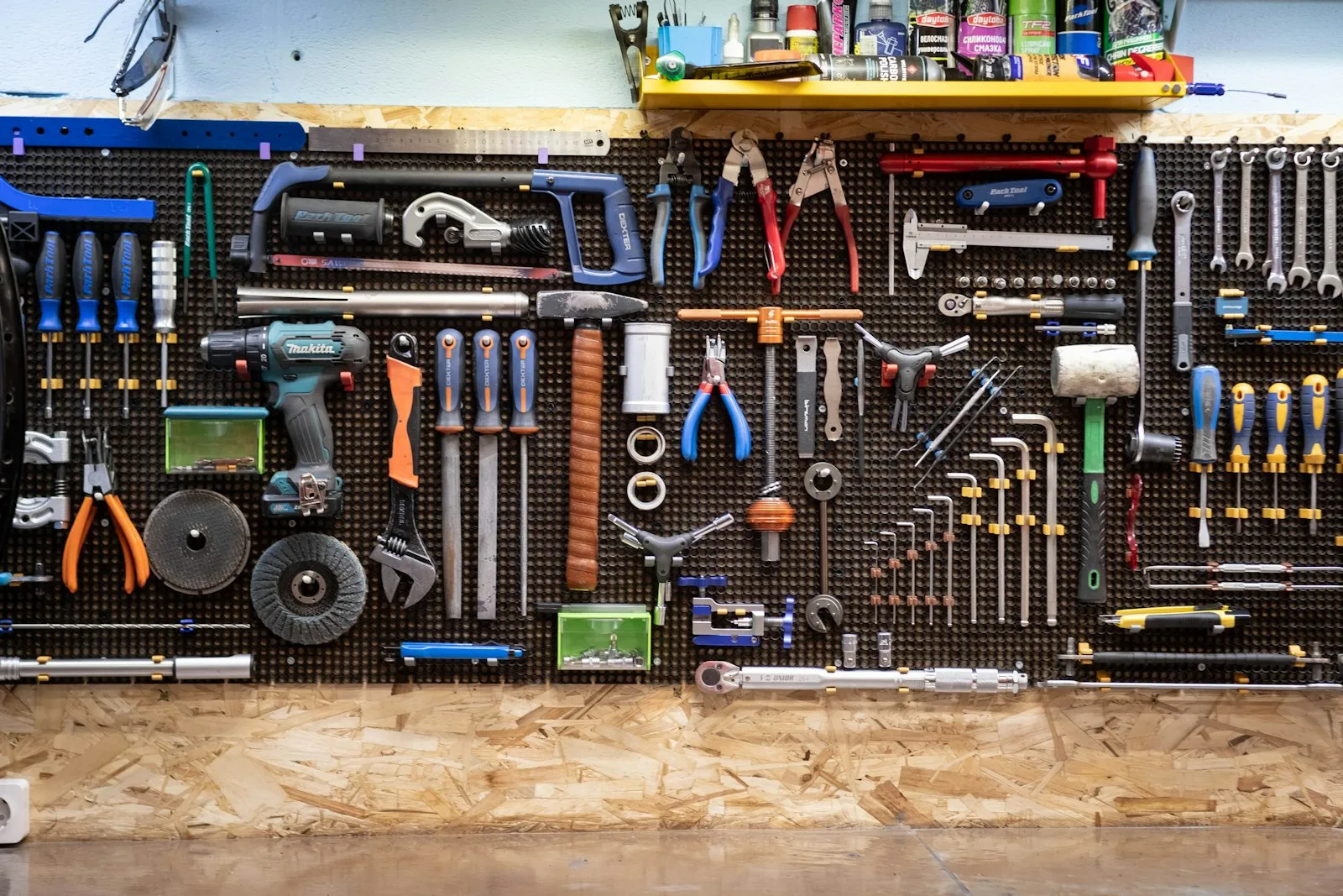 Parede de oficina com ferramentas manuais e elétricas organizadas em suportes